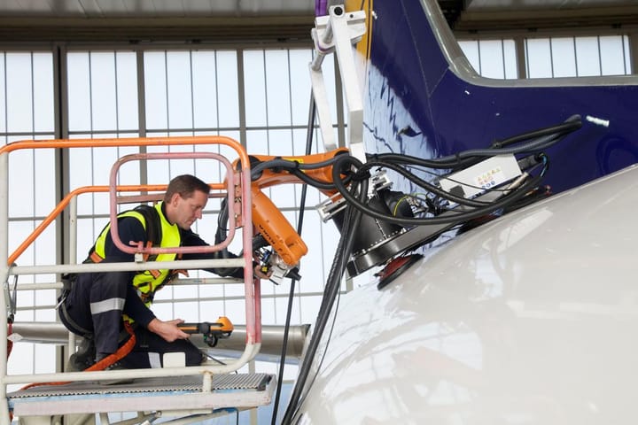 A mechanic is using robot arm to perform inspection on aircraft.
